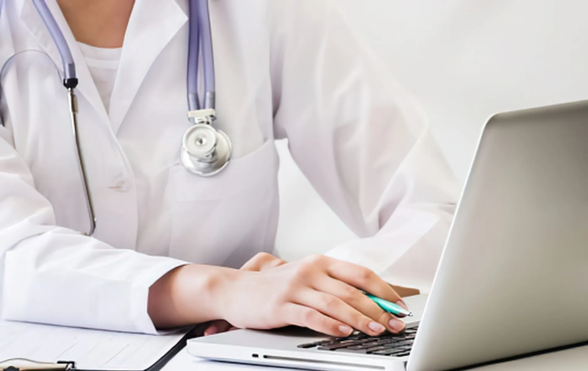 Doctor with stethoscope typing on laptop computer